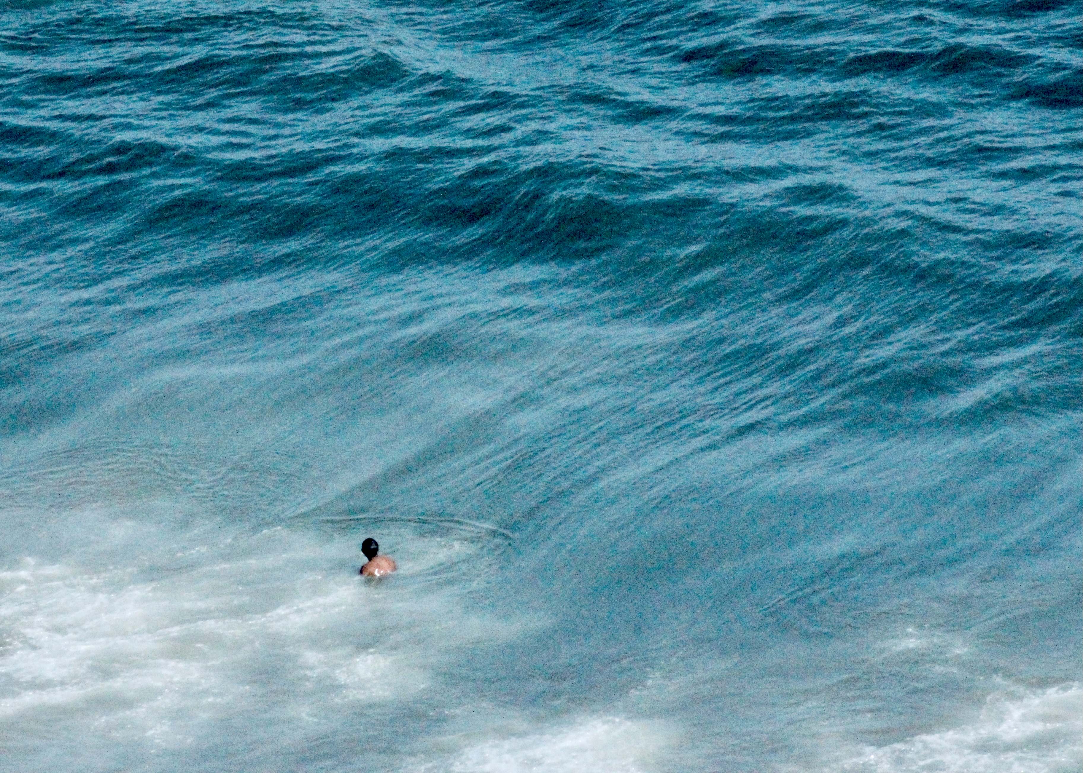 Lone swimmer in brilliant blue ocean water with rolling waves - The sea remembers photography series