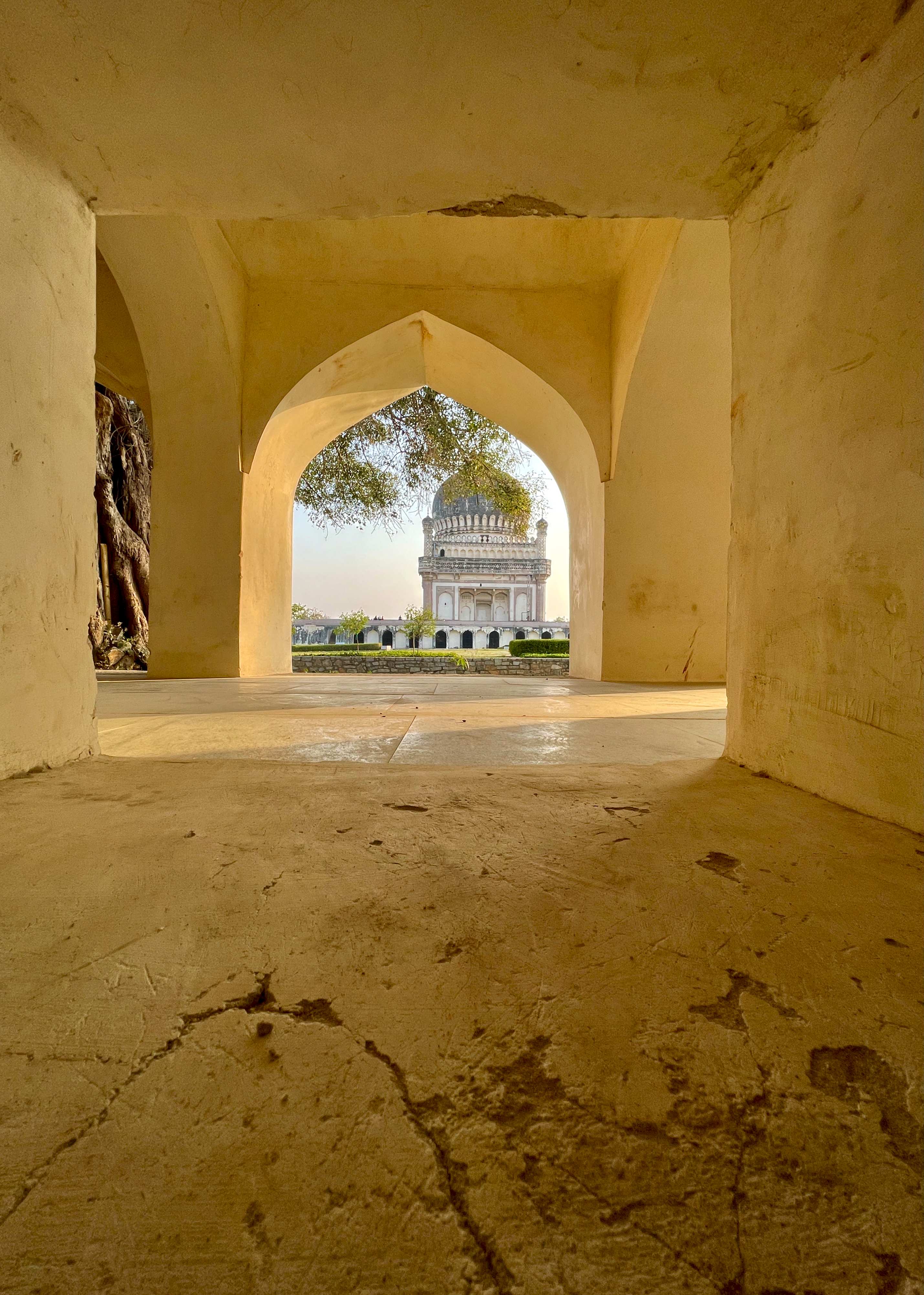 Golden-toned view through arched doorway framing distant domed building - Indo-Islamic architecture photography